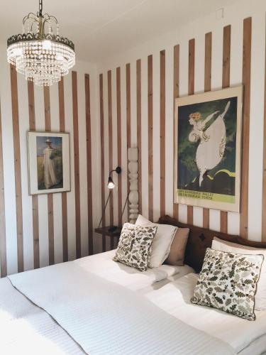 a bedroom with a bed with striped walls and a chandelier at Tallhöjden Hotel & Cottage Lodge in Simlångsdalen