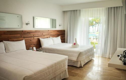 a hotel room with two beds and a window at Viva Tangerine by Wyndham, A Trademark All Inclusive in Cabarete