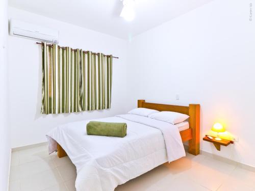 a white bedroom with two beds with white sheets at Residencial JL Maresias in Maresias