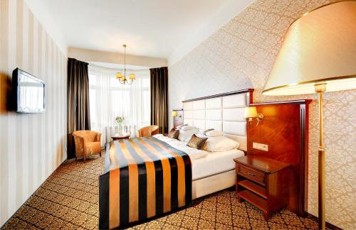 a hotel room with a bed and a desk at Grand Hotel Praha in Tatranská Lomnica