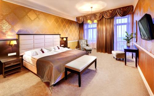 a bedroom with a large bed and a television at Grand Hotel Praha in Tatranská Lomnica