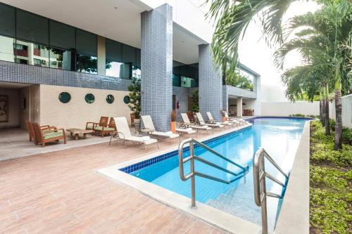 a swimming pool in front of a building at Beach Class Convention By Hôm - Antigo Bristol Recife in Recife