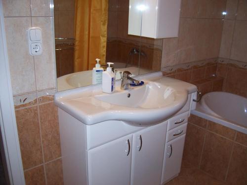 W łazience znajduje się biała umywalka i wanna. w obiekcie Júlia Vendégház w Zalakaros