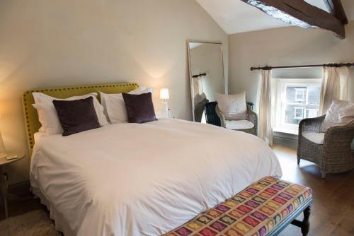 ein Schlafzimmer mit einem großen weißen Bett und einem Stuhl in der Unterkunft The Priory in Middleham