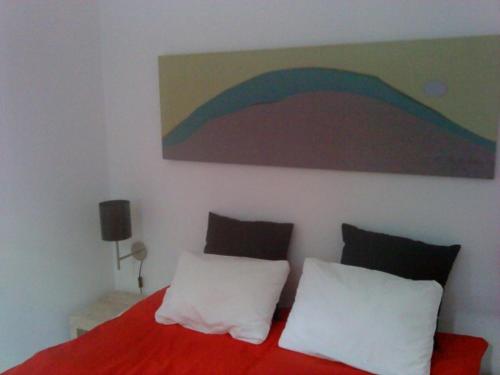 a bedroom with a red bed with a painting on the wall at Appartement coeur de ville in Ajaccio