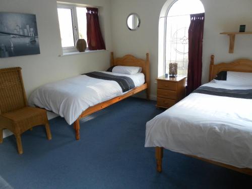a bedroom with two beds and a chair and a window at Country House Ashdene in Highworth