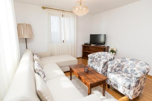 a living room with a white couch and two chairs at Apartments Villa Castello in Crikvenica