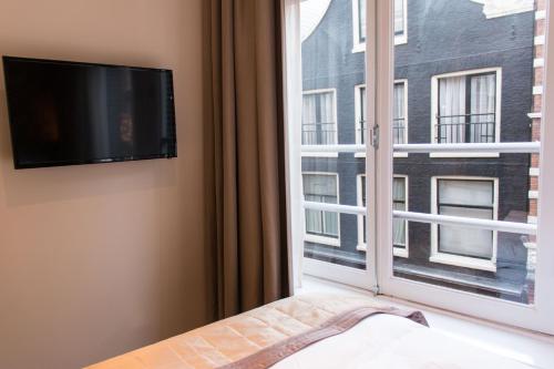 a bedroom with a window and a flat screen tv at Royal Plaza Hotel Amsterdam in Amsterdam