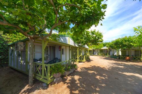 a green house with a tree in front of it at Camping Bungalows El Far in Calella