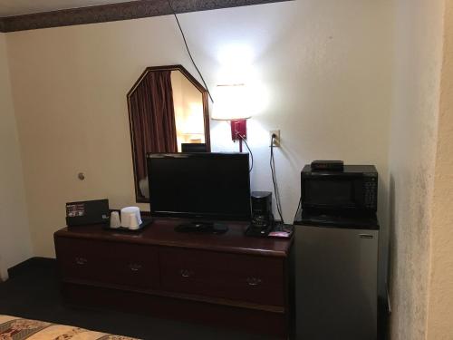 a room with a dresser with a television and a mirror at Budget Inn of Brownfield in Brownfield