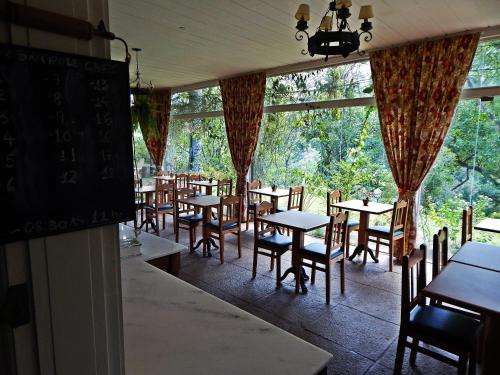 a dining room with tables and chairs and windows at Pousada Quinta dos Pássaros Itaipava in Itaipava