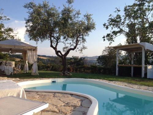 een zwembad in een tuin met een tuinhuisje bij Villa Tamara Country & Spa Suites in Montefiore Conca