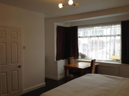 1 dormitorio con cama, escritorio y ventana en Repton Private Hotel, en Romford