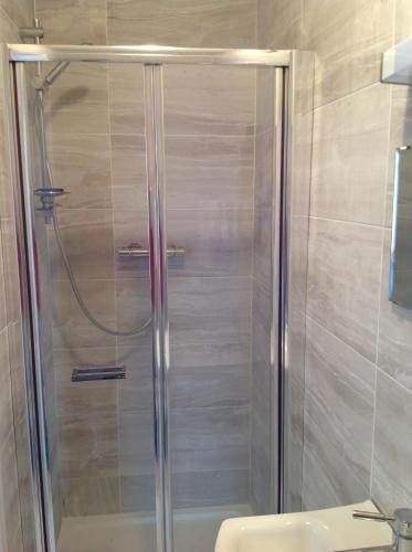 una ducha con puerta de cristal en un baño en Repton Private Hotel, en Romford