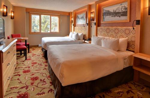 a hotel room with two beds and a television at Banff Ptarmigan Inn in Banff