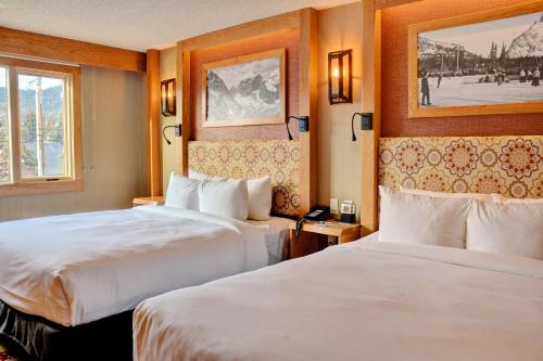 a hotel room with two beds and a picture on the wall at Banff Ptarmigan Inn in Banff