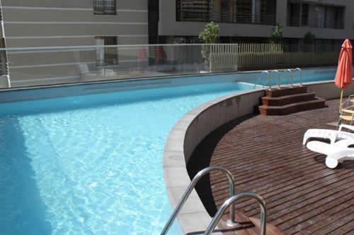 uma piscina com duas cadeiras e um guarda-sol em La Gloria 30. Las Condes em Santiago