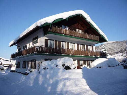 a building covered in snow with snow around it at Pension Bergblick in Ruhpolding