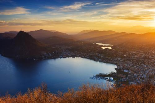 a view of a city and a lake at sunset at International au Lac Historic Lakeside Hotel in Lugano