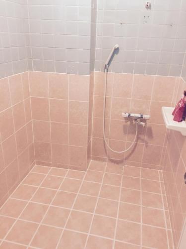 a shower with a hose in a bathroom at Holiday Homes TSUBOYA 1st in Naha