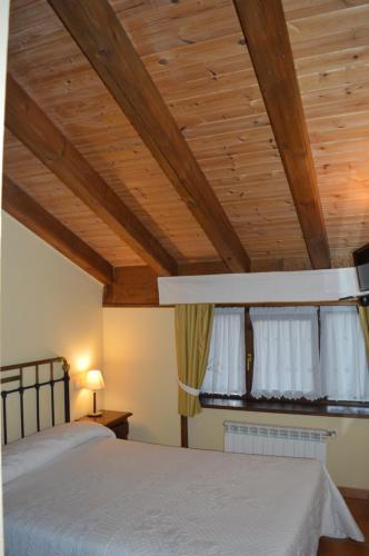 a bedroom with two beds and a wooden ceiling at Hostal Revinuesa in Vinuesa