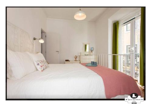 a bedroom with a white bed and a window at Canto do 28, Typical Apartment in Lisbon