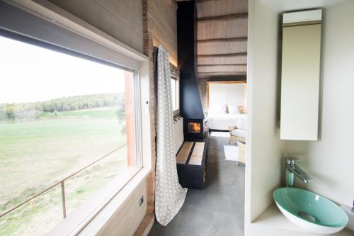 a bathroom with a view of a bed and a window at El Porxo de la Barraca in Caserras