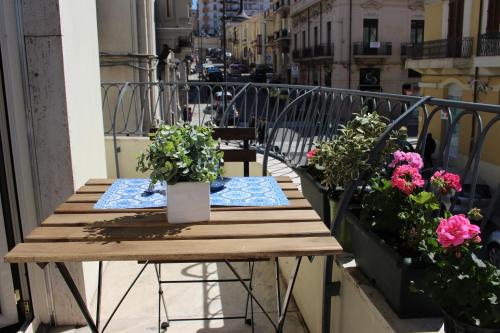 a wooden table on a balcony with flowers at La Casa di Aurora in Reggio Calabria