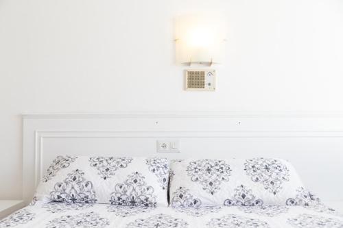 a white bed with two pillows and a white wall at Rey Fernando in Santiago de Compostela