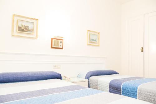 two beds in a room with white walls at Rey Fernando in Santiago de Compostela
