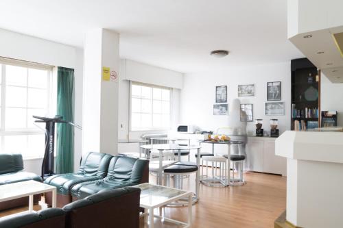 a living room with blue chairs and a kitchen at Rey Fernando in Santiago de Compostela