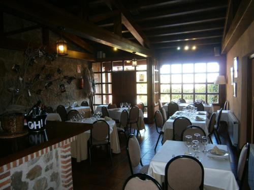 a dining room with white tables and chairs and windows at Hotel El Castrejon in Cebreros
