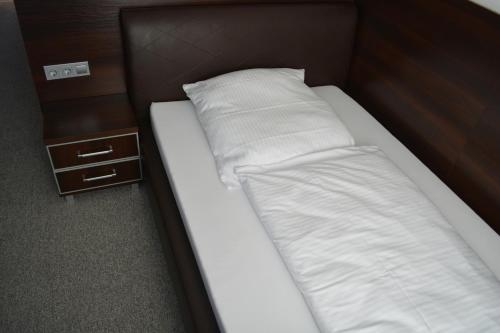 1 cama con sábanas blancas y almohadas junto a 2 mesitas de noche en B&D Hotel, en Hannover