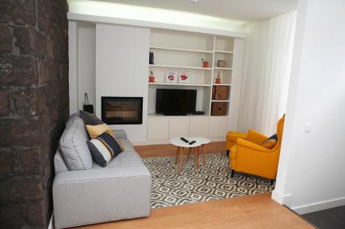 a living room with a couch and a television at Casa da Cisaltina in Povoação