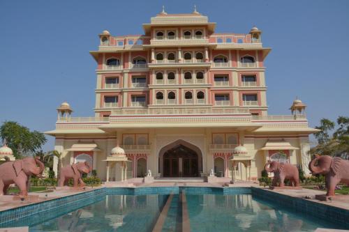 a building with elephant statues in front of a swimming pool at Indana Palace Jaipur in Jaipur