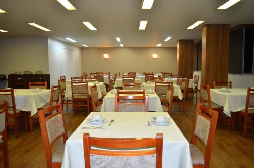 una sala da pranzo con tavoli e sedie bianchi di Niteroi Palace Hotel a Niterói