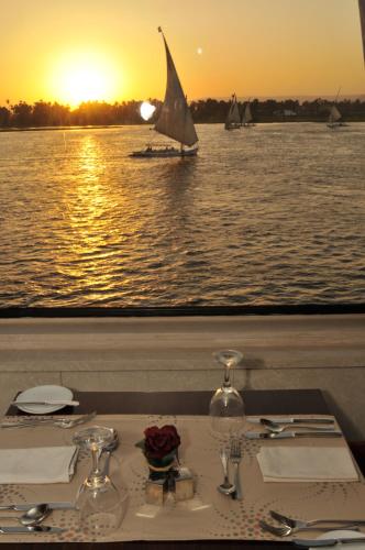 a table with a view of the water with a sail boat at M/Y Alexander The Great Nile Cruise - 4 Nights Every Monday From Luxor - 3 Nights Every Friday from Aswan in Luxor