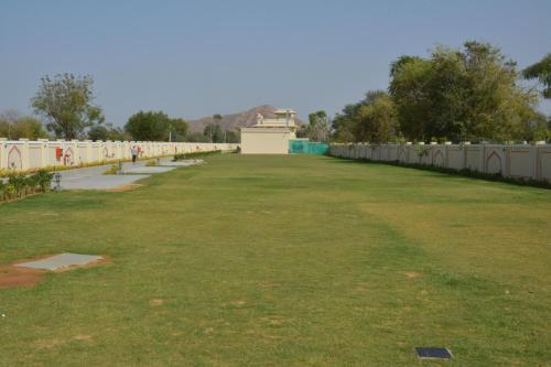 a large field of grass with a fence in the background at Indana Palace Jaipur in Jaipur
