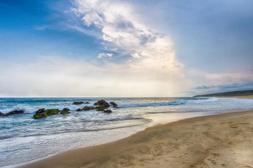 a beach with rocks in the water and the ocean at Posada Real Puerto Escondido in Puerto Escondido