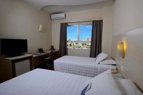 a hotel room with two beds and a window at Golden Blue Hotel in Londrina