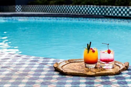 two cocktails on a tray next to a swimming pool at Majeka House Boutique Hotel by The Living Journey Collection in Stellenbosch