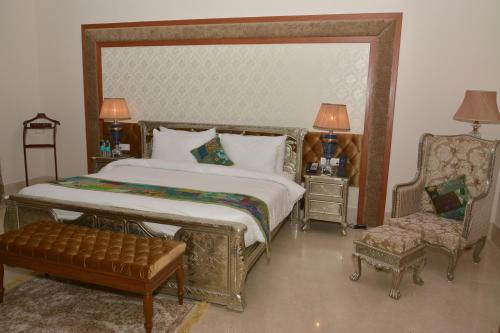 a bedroom with a large bed and a chair at Indana Palace Jaipur in Jaipur