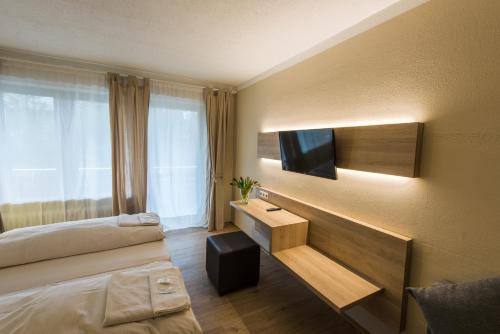 a hotel room with a bed and a tv at Ahorn Hotel in Munich