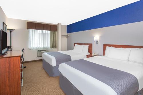a hotel room with two beds and a flat screen tv at Baymont by Wyndham Dubuque in Dubuque