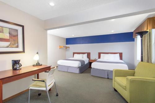 a hotel room with two beds and a desk at Baymont by Wyndham Dubuque in Dubuque