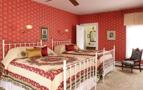 two beds in a bedroom with red wallpaper at The Queen Victoria in Cape May