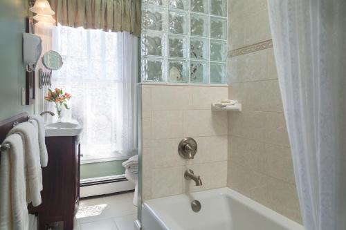 a bathroom with a tub and a shower with a window at The Queen Victoria in Cape May