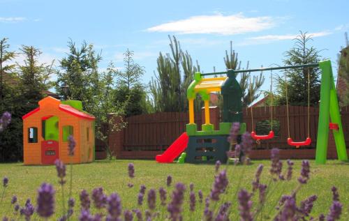 a playground with two play equipment in a yard with purple flowers at Apartamenty Fala in Rowy
