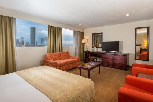 a hotel room with a bed and a chair and a television at Hotel Dann Av. 19 in Bogotá