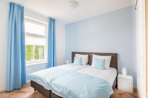 MeliskerkeにあるMeliskerke vakantiewoningのベッドルーム1室(青いカーテン付きの大型ベッド1台付)